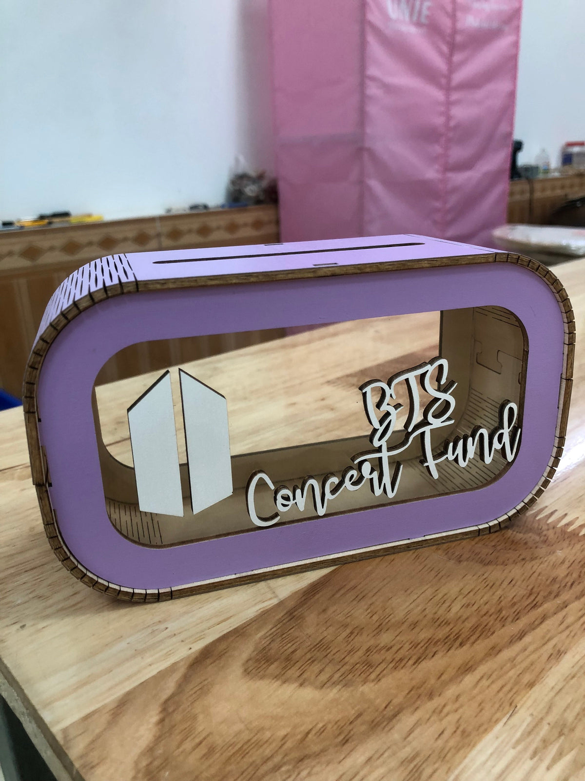 Photo on wooden desk of purple BTS concert piggybank