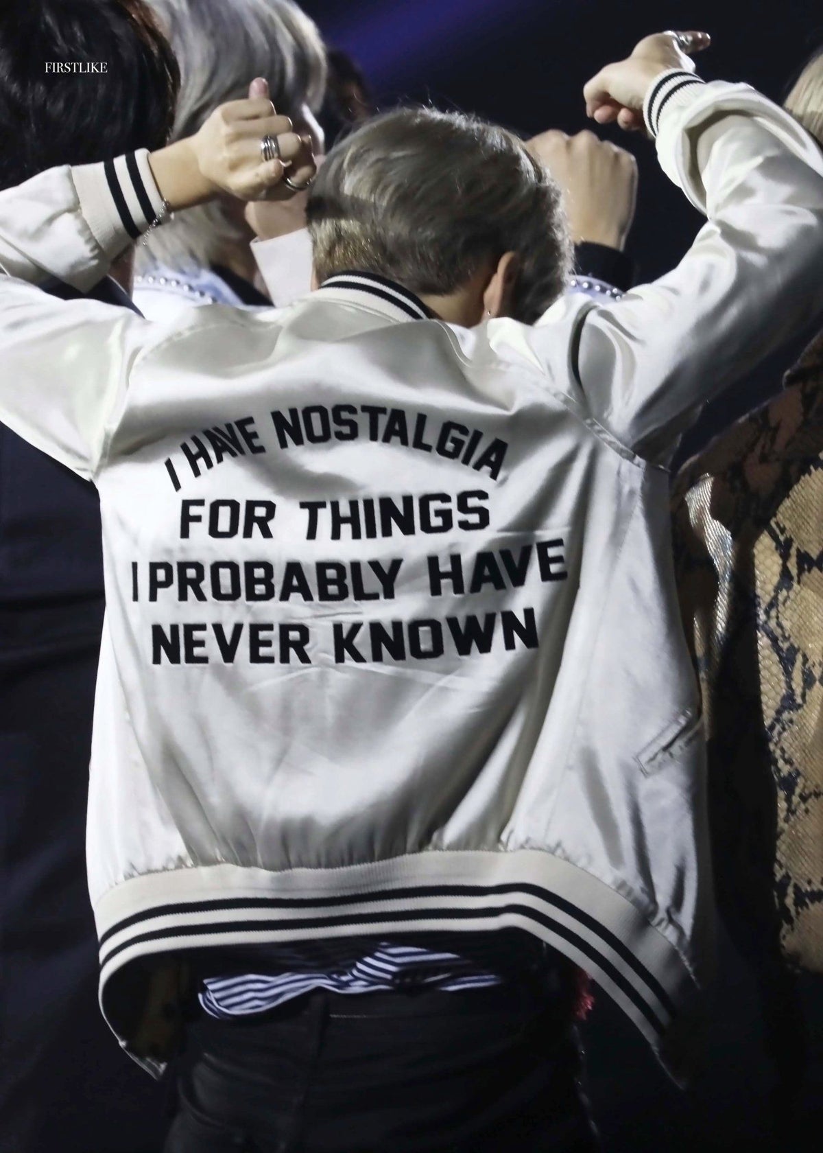 Jimin with hands up wearing his nostalgia bomber jacket