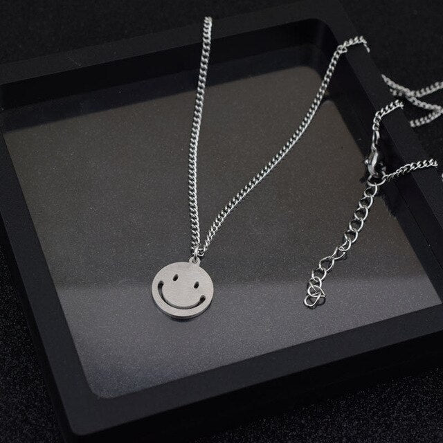 J-Hope 'Sunshine' smiley necklace displayed elegantly on a stylish black tray with a close-up of the pendant and a performer holding a microphone.