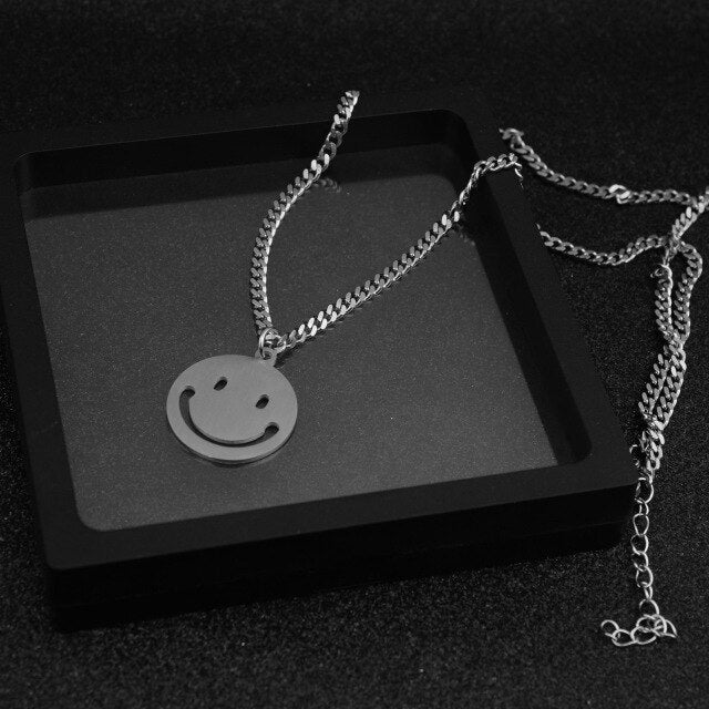 J-Hope 'Sunshine' smiley necklace laid out on a dark surface, highlighting its shiny smiley face pendant and chain.
